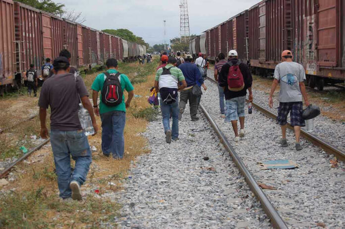 People walking along train tracks carrying backpacks