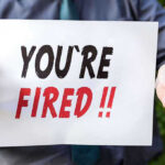 Person holding YOURE FIRED sign