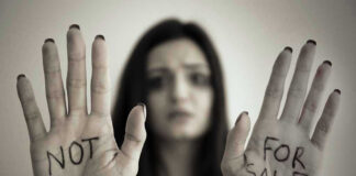 Handcuffed woman shows NOT FOR SALE on her palms