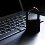 A padlock resting on a laptop keyboard in a dimly lit environment