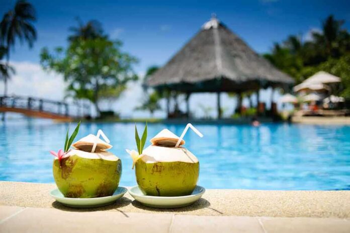 shutterstock_129923588.jpg Two coconut drinks with straws beside a swimming pool