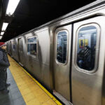 Man waiting at subway platform with departing train