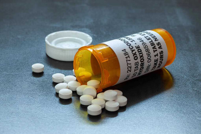 Open pill bottle with white tablets spilled out