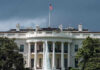 White House with American flag and fountain stormy sky