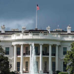 White House with American flag and fountain stormy sky