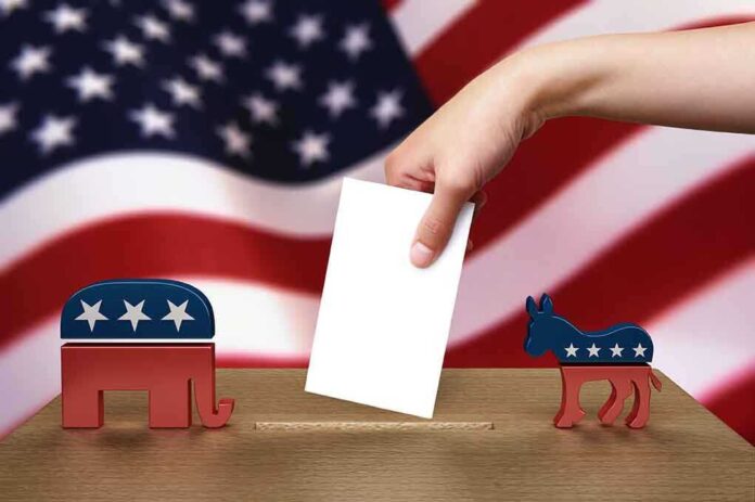 shutterstock_103487231.jpg A hand placing a ballot into a box with political symbols on either side against a backdrop of the American flag