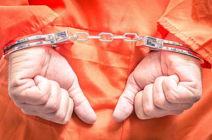 Hands in handcuffs wearing an orange jumpsuit