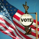 A vintage Vote sign in front of an American flag