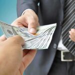 Two hands exchanging cash in a business setting
