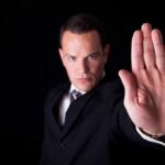 Trump SUSPENDS All Aid to Major Nation Businessman in a suit making a stop gesture with his hand