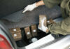 Amazon Turns Trillion-Dollar Crime Empire Person discovering wrapped packages in a car trunk.