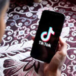 In-N-Out KILLS Number 67 — TikTok Chaos Hand holding phone showing TikTok logo.
