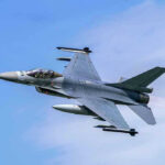 Fighter Jet Mystery: New Missile Spotted Jet fighter flying through clear blue sky.