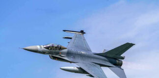 Jet fighter flying through clear blue sky.