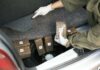 Law enforcement officer inspecting packages in a car trunk