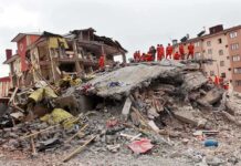 Rescue workers in orange uniforms on a collapsed building site after an earthquake