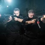 Horrifying Spectacle Reveals Taliban’s True Nature Two tactical operators aiming firearms in a dimly lit urban setting