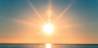 A serene sunrise over a calm ocean with vibrant colors in the sky