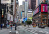 Times Square street scene with storefronts and advertisements.