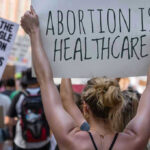 Protestors holding signs about womens rights and healthcare.