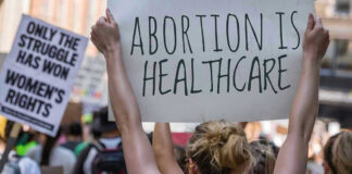 Protestors holding signs about womens rights and healthcare.