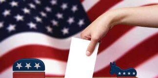 A hand placing a ballot into a box with political symbols on either side against a backdrop of the American flag