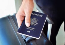 A person holding a United States passport next to a suitcase
