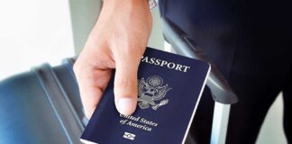 A person holding a United States passport next to a suitcase