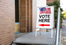 Voter ID Backlash: Hidden Agenda Uncovered Vote Here sign with arrow and American flag.