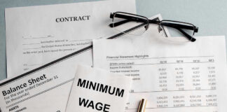 Documents and glasses on table with Minimum Wage paper.