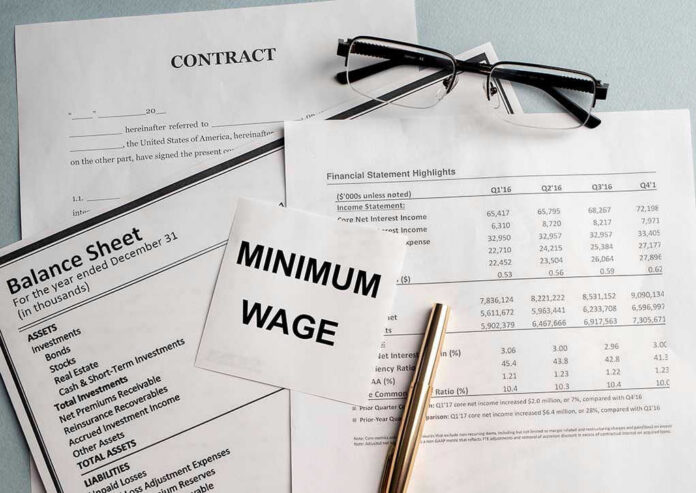 Documents and glasses on table with Minimum Wage paper.