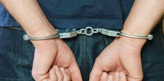 Person in handcuffs behind their back.