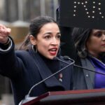 AOC’s Bold 2028 Move Shocks Democrats A woman passionately speaking at a rally with a sign in the background
