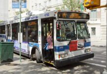 A woman boarding a clean air hybrid electric bus at a city stop