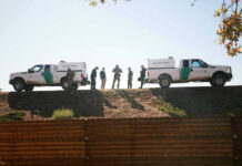 Border Patrol vehicles and agents on a ridge.