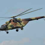 Army Training Route…Or VIP Joyride? Camouflage military helicopter in flight against blue sky.