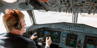 Pilot in cockpit operating airplane controls.
