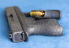 Handgun on blue fabric with visible bullet cartridge.