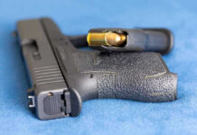 Handgun on blue fabric with visible bullet cartridge.