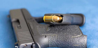 Handgun on blue fabric with visible bullet cartridge.