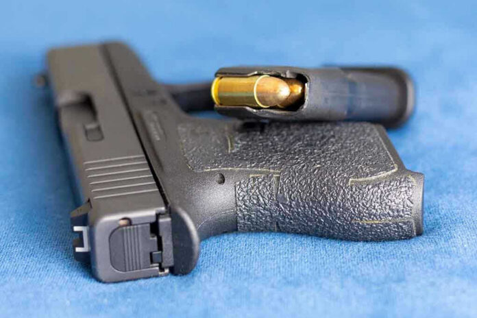 Handgun on blue fabric with visible bullet cartridge.