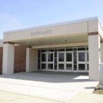 Entrance of a modern school building with glass doors and a brick facade