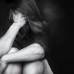Negative People Inflict 50% Higher Dementia Risk A person sitting with their knees drawn up, covering their face with their hands, expressing emotional distress.