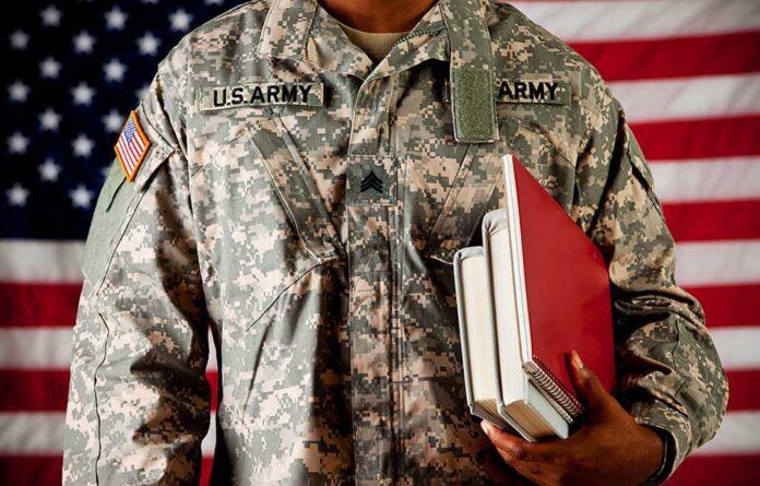 shutterstock_184208507.jpg A soldier in a U.S. Army uniform holding books in front of an American flag