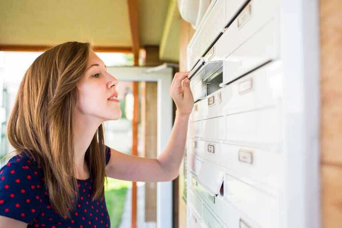 shutterstock_202541005.jpg A woman checking her mailbox in an outdoor setting