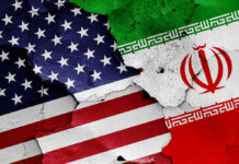 UNEXPECTED Reversal Rattles Tehran’s War Machine Cracked American and Iranian flags painted on a wall.
