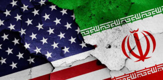 Cracked American and Iranian flags painted on a wall.