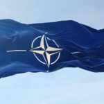Closed-Door NATO Clash Stuns Europe NATO flag waving against blue sky.