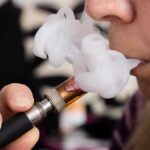 Chinese Vape Ban Triggers Catastrophic Price Spike Close-up of a person vaping, exhaling smoke clouds