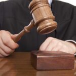 A judge holding a gavel above a wooden block